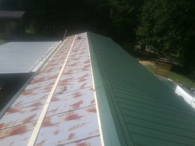 Old rusted panels beside newly installed green metal roofing — Wind Damage Roof Repair by Roofing Brothers in West Fork