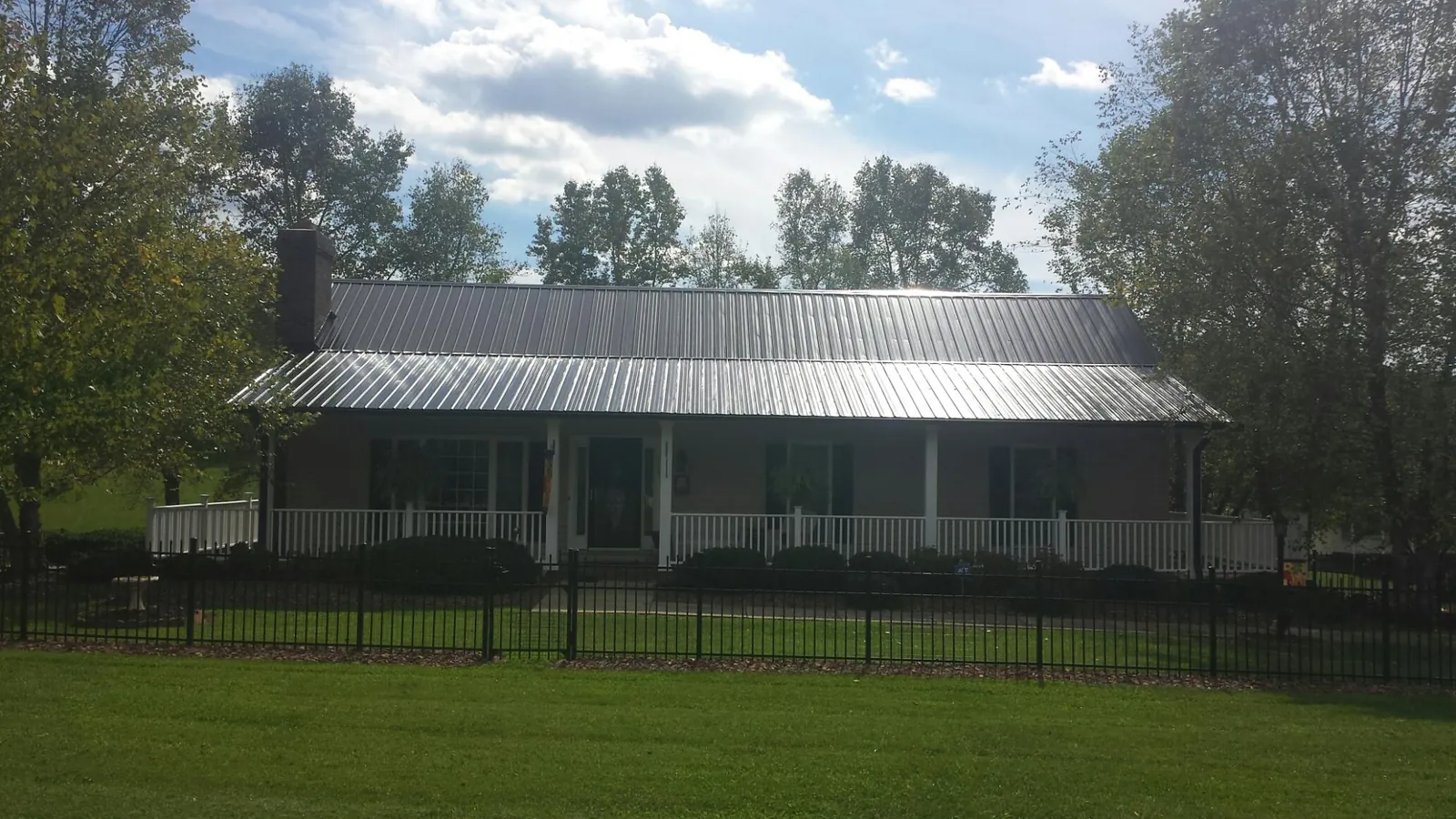 Gray metal roof on a brick ranch with a full width front porch — Gutter Guard Installation work by our crew in West Fork